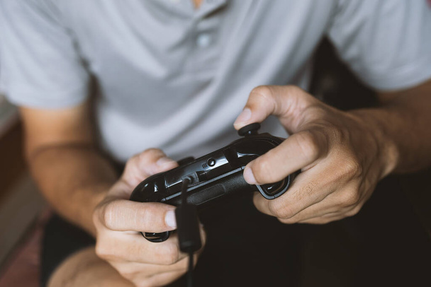 closeup hand man holding black joystick. play game. soft-focus and over light in the background - 写真・画像