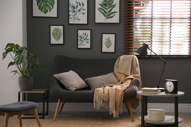 Beautiful artworks and comfortable sofa in stylish room. Interior design - Fotó, kép