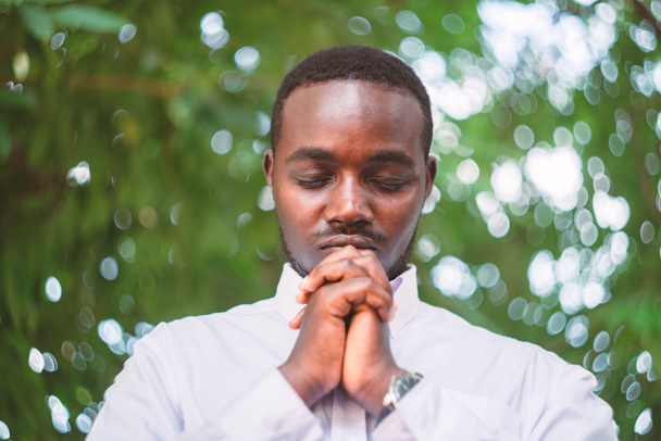 Hombre africano rezando a Dios en la naturaleza verde - Foto, imagen