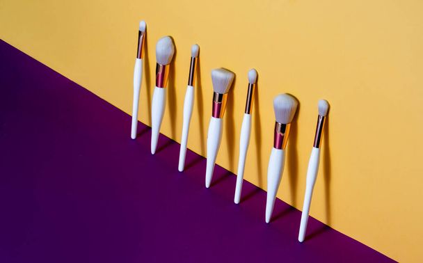 Makeup flat lay brushes yellow and purple background. Horizontal top view copyspace. Beauty and make up - Photo, Image