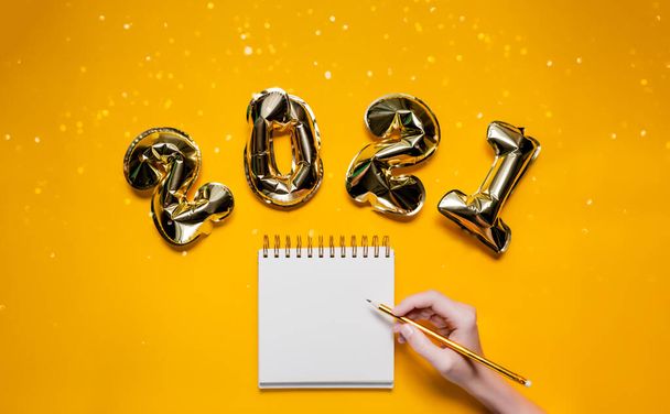 Golden balloons on bright yellow background with bokeh and sparkles. Wishlist with resolution and new year concept. Top horizontal view background - Foto, Imagem