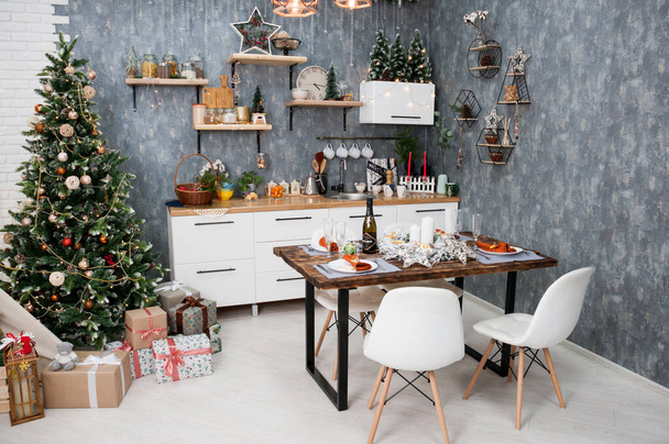Interior de año nuevo, árbol de Navidad decorado con regalos en la cocina y una mesa festiva
 - Foto, Imagen