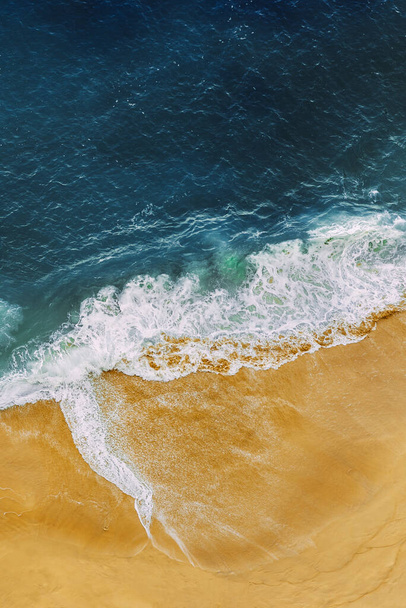 Beautiful sandy beach with blue sea, vertical view. Drone view of tropical blue ocean beach Nusa penida Bali Indonesia. Lonely sandy beach with beautiful waves. Beaches of Indonesia. Copy space - Foto, immagini