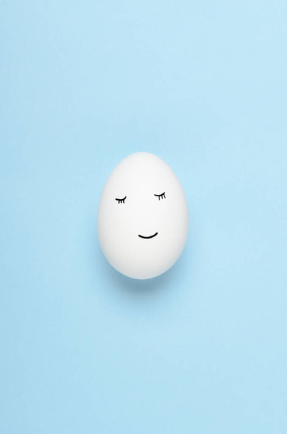 Kawaii faces on white eggs on a blue background. Cartoons, decoration food for children. Top view, flat lay - Fotó, kép