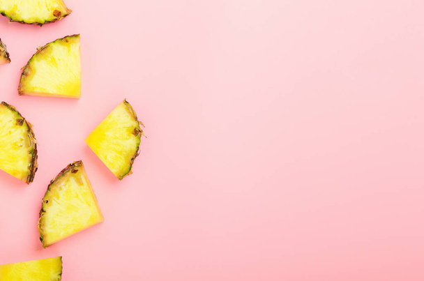 Ananas plakjes op een roze achtergrond. Tropisch sappig exotisch gezond fruit. Kopieerruimte, bovenaanzicht, flat lay - Foto, afbeelding