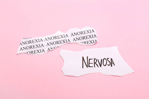 Trozos de papel con texto ANOREXIA NERVOSA sobre fondo de color
 - Foto, imagen