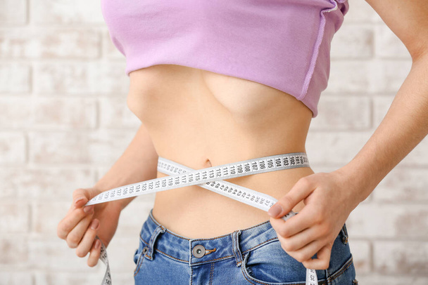 Mujer midiendo su cintura, primer plano. Concepto de anorexia
 - Foto, imagen