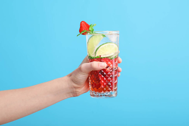 Hand with glass of fresh strawberry lemonade on color background - Photo, Image