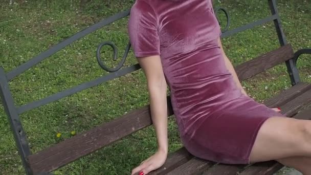 Elegante junge Brünette entspannt sich auf Bank im Park - Filmmaterial, Video