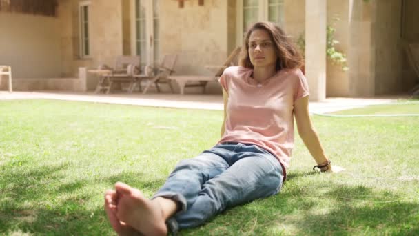 Young happy beautiful woman relaxing on the grass near her country house - Materiał filmowy, wideo