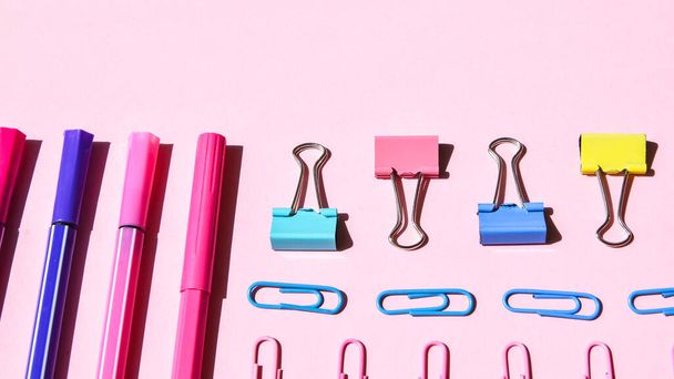 Different office or school supplies on pink background. Copy space for text, pencil paper clip stickers markers and clothespin - Фото, зображення