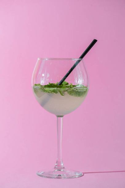 Mojito alcohol cocktail, tropical beverage with ice, mint and lime on pastel pink background with copy space - Photo, Image
