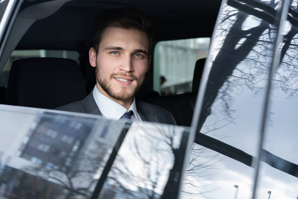 Young handsome businessman is sitting in luxury car - Zdjęcie, obraz