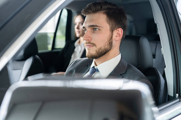 Success in motion. Handsome young man in full suit smiling while driving a car. - 写真・画像