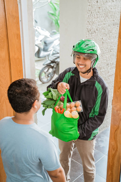 male courier delivering grocery to customer - Fotó, kép
