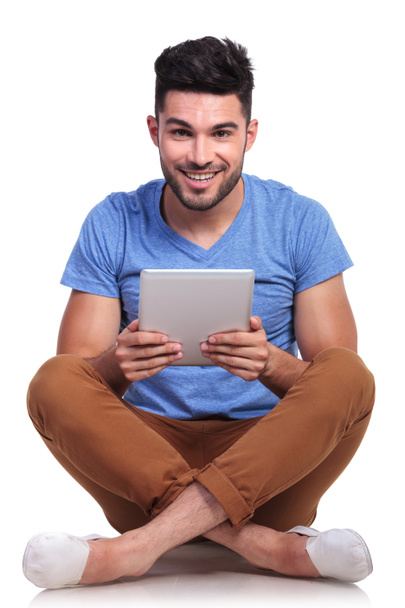 Zittende jonge man met Tablet PC pad lachende - Foto, afbeelding