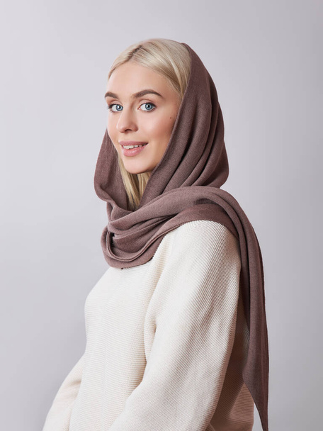European Muslim woman with a blonde hair in a headscarf shawl dressed on her head. Beautiful girl in sweater with soft skin, natural cosmetics - Valokuva, kuva