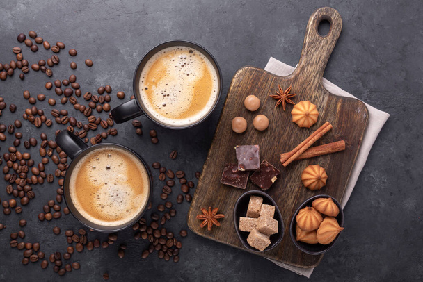 Coffee cups, coffee beans, various sweets and spice on stone background. Top view. Copy space - Image - Foto, afbeelding