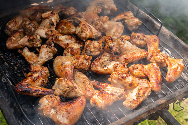 Viele leckere, leckere, herzhafte Hühnerflügel mit angenehmem Geruch und Fleischdunst auf dem Grill im Dorf - Foto, Bild