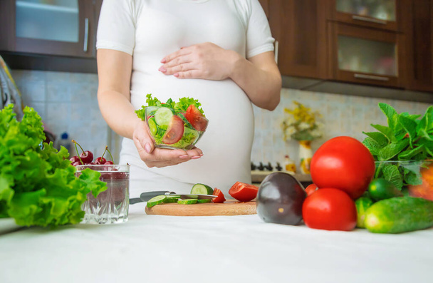Μια έγκυος γυναίκα τρώει λαχανικά και φρούτα. Επιλεκτική εστίαση. Τρόφιμα. - Φωτογραφία, εικόνα