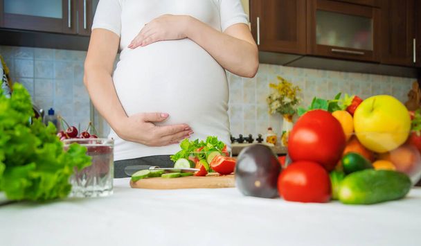 A pregnant woman eats vegetables and fruits. Selective focus. Food. - Photo, image
