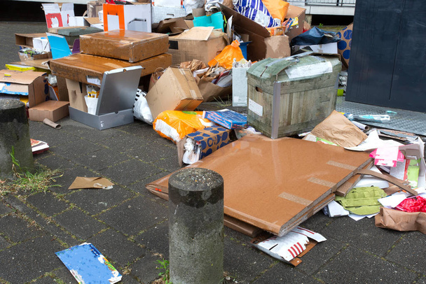 Grote stapel afval naast volle container op smerige straat, oud papier - Foto, afbeelding
