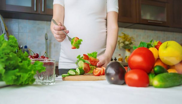 Une femme enceinte mange des légumes et des fruits. Concentration sélective. Produits alimentaires. - Photo, image