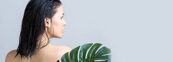 Piękna kobieta z naturalnym zielonym portretem liścia palmy. Moda, piękno, makijaż, kosmetyki. - Zdjęcie, obraz