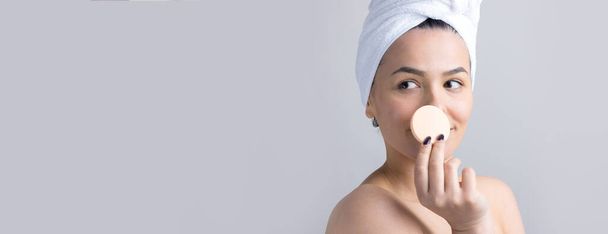 Beauty portrait of woman in white towel on head with a sponge for a body in view of a pink heart. Skincare cleansing eco organic cosmetic spa relax concept. - Fotó, kép
