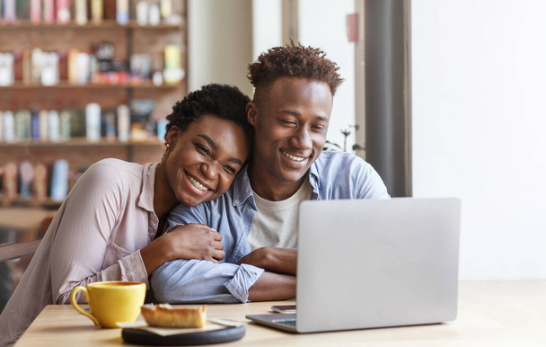 afro americano ragazza abbracciare il suo fidanzato mentre guardando film su computer portatile a caffè - Foto, immagini