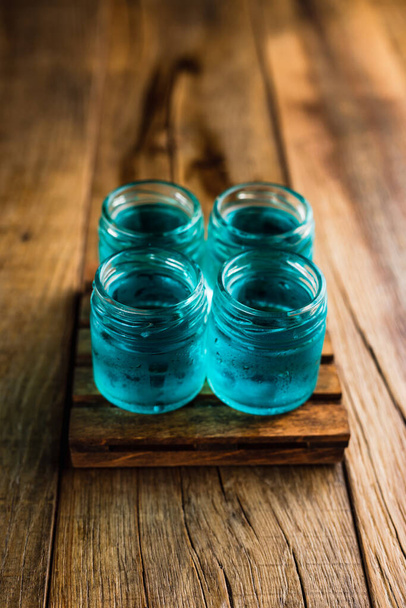 Blue colored alcoholic shooters, or shot drinks on wooden table - Foto, imagen