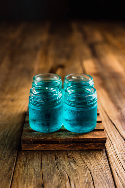 Blue colored alcoholic shooters, or shot drinks on wooden table, with copy space - Foto, imagen
