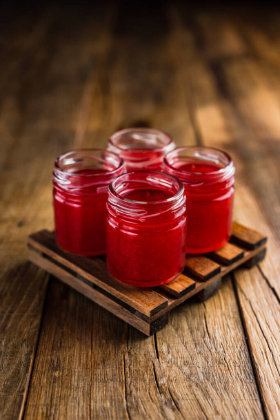 Red colored alcoholic shooters, or shot drinks on wooden table - Foto, imagen