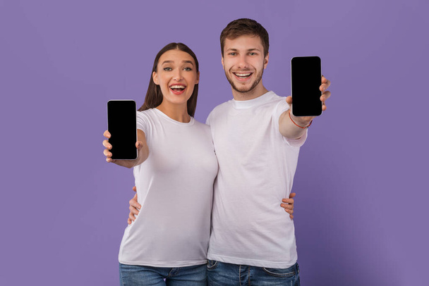 Gli sposi felici che mostrano lo schermo del cellulare vuoto alla fotocamera - Foto, immagini