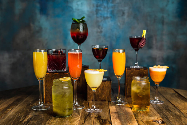 A great variety of alcoholic cocktails in different glasses on a wooden surface - Foto, afbeelding