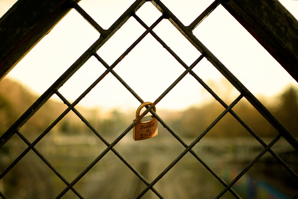 backlight of a closed padlock on a fence in a sunset - Photo, Image