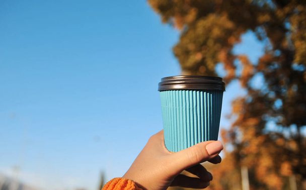 Női kéz papír csésze kávé őszi háttér. - Fotó, kép