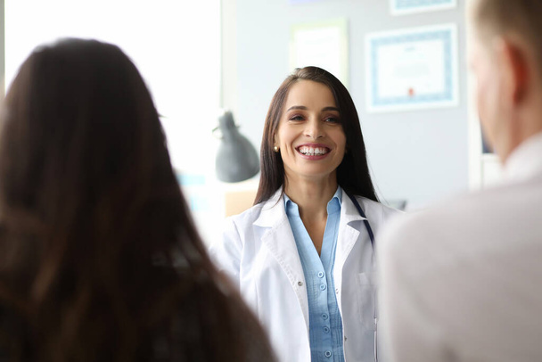 Веселая женщина-врач разговаривает с коллегами на работе
 - Фото, изображение