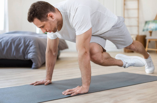 Sportowy człowiek szkolenia w domu Wykonywanie Running Plank Ćwiczenia - Zdjęcie, obraz