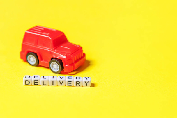 Wystarczy zaprojektować czerwony samochód zabawki i napis DOSTAWA słowo izolowane na żółtym tle kolorowe. Zakupy internetowe zakup online e-commerce pakiety koncepcja usługi dostawy. Przestrzeń kopiowania - Zdjęcie, obraz