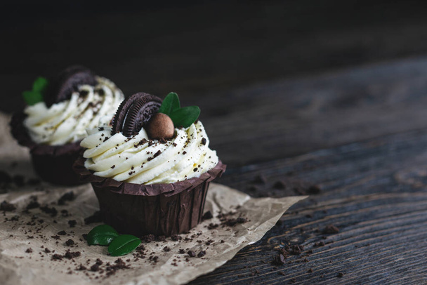 Lekkere cupcake, versierd met chocoladekoekjes op een donkere houten achtergrond. Plaats voor tekst. - Foto, afbeelding