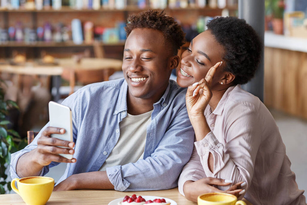 Pareja afroamericana tomando selfie en una cita romántica en una cafetería
 - Foto, imagen