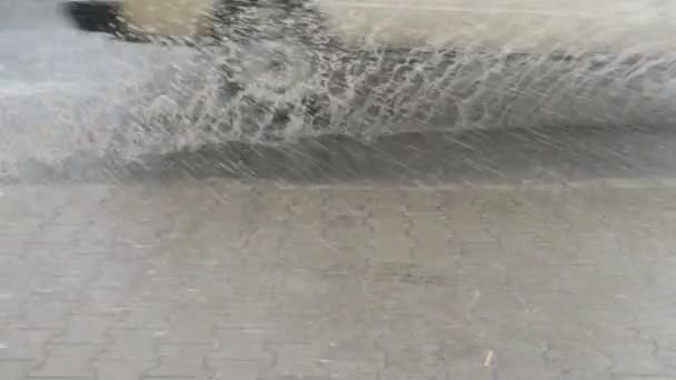 Fluxo de água e poeira de água na estrada durante uma tempestade. Rodas de carros cortando fluxos de água. Salpicos de água na calçada
. - Filmagem, Vídeo