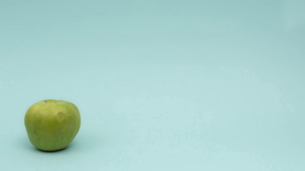 Stop motion animation of green apple turning around on blue - Footage, Video