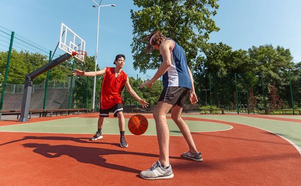 Dos deportistas milenarios jugando al baloncesto en el patio al aire libre
 - Foto, Imagen
