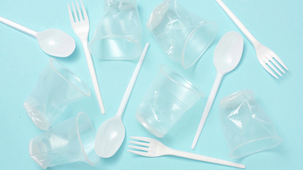 Stop motion animation of plastic cups, spoons and forks on blue - Video