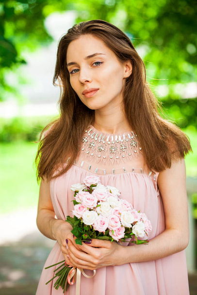 Close up portrait of a young brunette woman in pink dress - 写真・画像