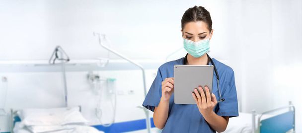 Masked young nurse doctor using a tablet - Foto, Imagen
