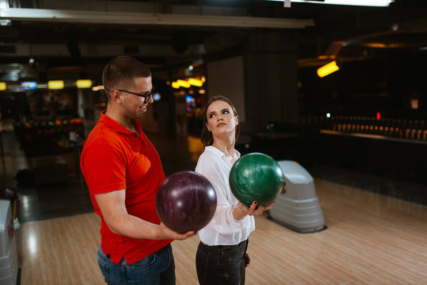 Um belo caucasiano homem e mulher em uma pista de bowling com bolas. Amor e recreação
 - Foto, Imagem
