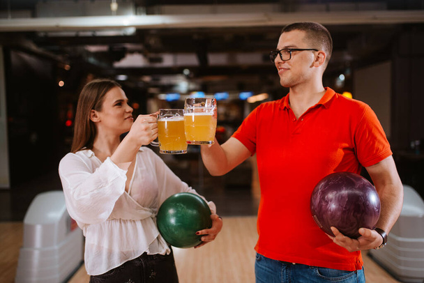 Běloška a muž na bowlingové dráze s hrnky piva. Láska a bowling - Fotografie, Obrázek